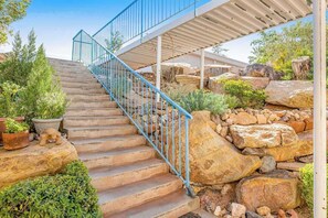 A staircase with a metal railing leading to a covered area with a view of a rocky landscape. - Sunny 2BR Mountainview Zion National Park (St. George)