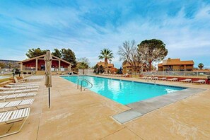A swimming pool with lounge chairs and a covered area, surrounded by buildings and trees. - 1 BR condo withshared pools, sports courts (Saint George)