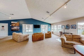 Ein geräumiges Wohnzimmer mit hohen Decken, großen Fenstern und einer vielfältigen Sitzmöbel-Auswahl, darunter Sofas und ein Couchtisch.