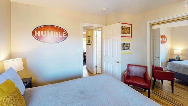 Un dormitorio con una cama, una silla roja, una puerta y un cartel en la pared que dice 'HUMBLE'.