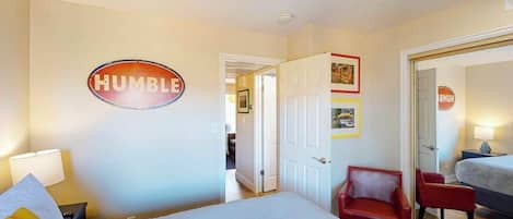 Une chambre à coucher avec un lit, une chaise rouge, une porte et un panneau mural sur lequel on peut lire le mot « HUMBLE ».