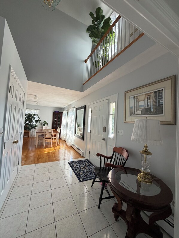 A spacious hallway with a dining area, a staircase, and a large plant.