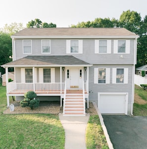 A two-story house with a front porch, a garage, and a well-maintained lawn.