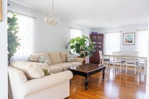 A living room with a sofa, coffee table, dining table, chairs, and a cabinet.