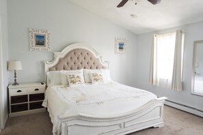 A bedroom with a bed, nightstand, lamp, and decorative pillows.