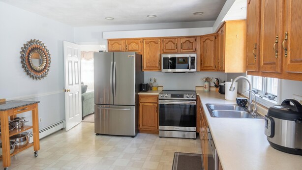 A modern kitchen with stainless steel appliances, wooden cabinets, and a large window providing natural light.