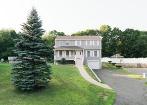 A two-story residential house with a front porch, a garage, and a well-maintained lawn.