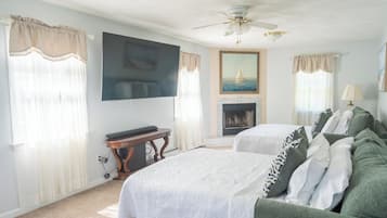 Ein Hotelzimmer mit zwei Betten, einem Flachbildfernseher, einem Kamin und einem Deckenventilator.