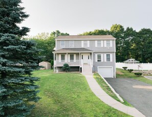 A two-story residential house with a front porch, a garage, and a well-maintained lawn.