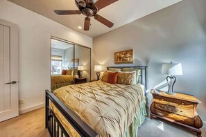 A bedroom with a bed, bedside tables, a ceiling fan, a mirror, and a painting on the wall. - Lovely 3BR Mountainview Zion National Park 2nd-fl (Santa Clara)