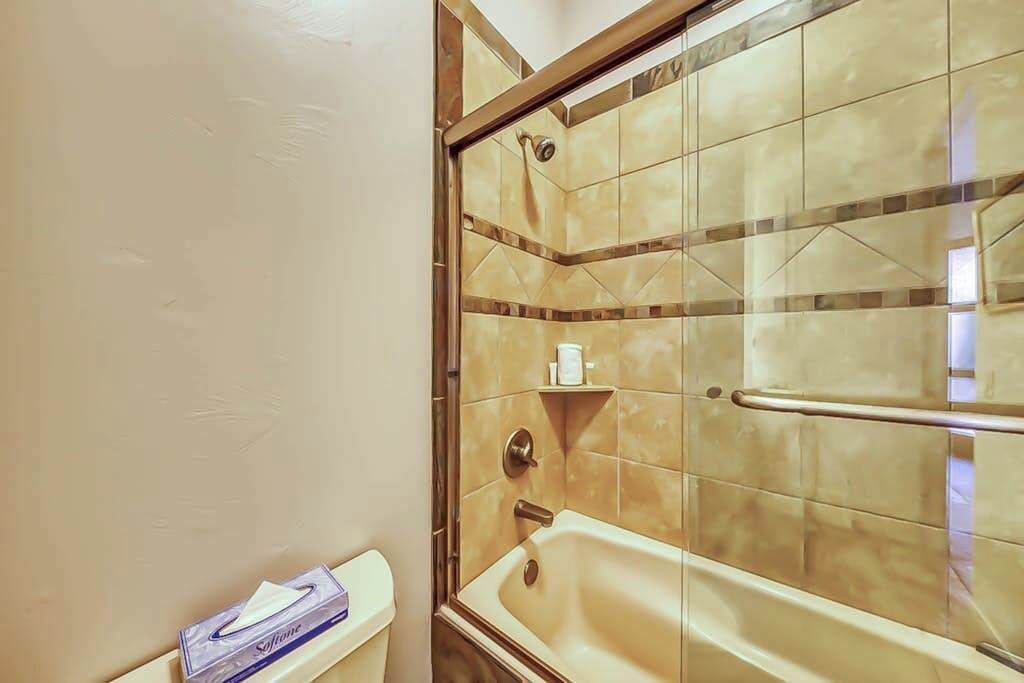 A bathroom with a glass-enclosed shower, a bathtub, and a toilet.