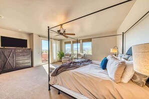 Een slaapkamer met een hemelbed, een televisie, een bureau en uitzicht op de omgeving.