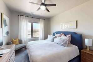 A bedroom with a bed, a desk, a chair, a ceiling fan, and a window with curtains. - Townhouse with resort amenities, private hot tub (Hurricane)