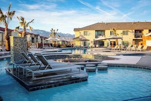 A pool area with lounge chairs, a hot tub, and a building with a mountain backdrop. - Townhouse with resort amenities, private hot tub (Hurricane)