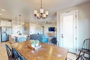 A spacious kitchen with a wooden dining table, modern appliances, and pendant lighting. - Townhouse with resort amenities, private hot tub (Hurricane)