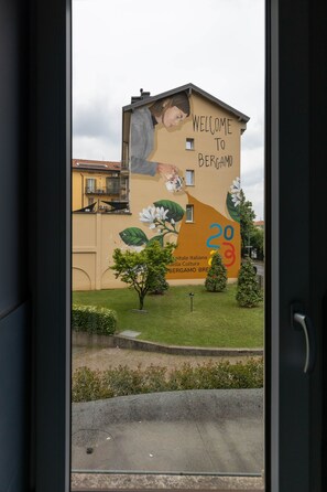 Ein Gebäude mit Wandgemälde, das Besucher in Bergamo willkommen heißt, mit einer Hand, die ein Getränk einschenkt, und der Zahl '20'.