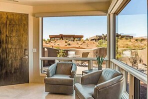A modern interior with a large window offering a view of a desert landscape and a building in the distance. - Mountain View Studio Near Zion National Park (St. George)
