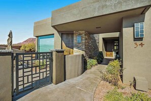 A modern building with a stone facade, a gated entrance, and a clear view of the surrounding landscape. - Mountain View Studio Near Zion National Park (St. George)