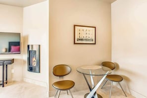 A modern room with a fireplace, a framed artwork, and a glass table with chairs. - Mountain View Studio Near Zion National Park (St. George)