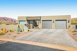 A modern two-story house with a garage, a driveway, and desert landscaping. - Mountain View Studio Near Zion National Park (St. George)