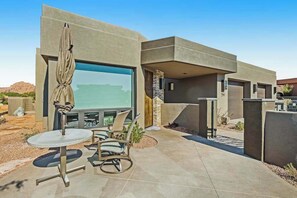 A modern outdoor patio with a seating area, a large screen, and a view of the desert landscape. - Mountain View Studio Near Zion National Park (St. George)