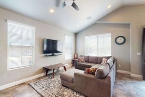 Ein Wohnzimmer mit einer Couch, einem Fernseher und einem Deckenventilator.