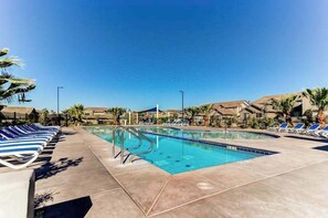A swimming pool with lounge chairs and palm trees, surrounded by buildings. - 3BR townhouse near Zion National Park (Washington)