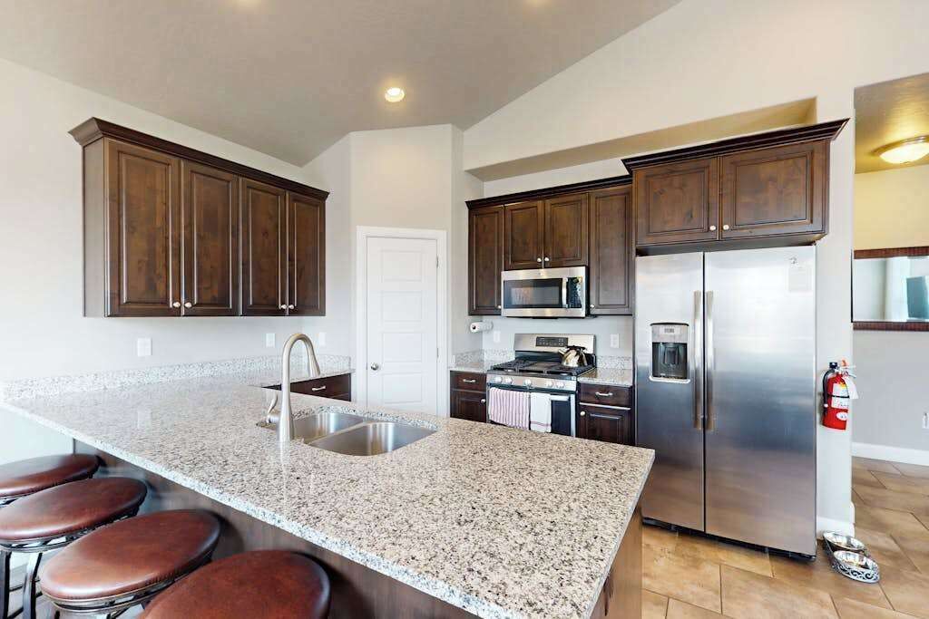 A kitchen with granite countertops, stainless steel appliances, and dark wood cabinets.