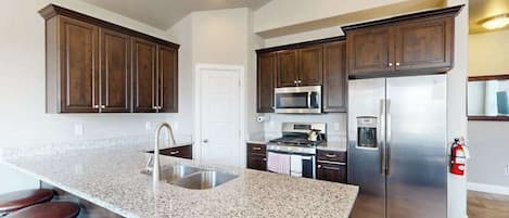 A kitchen with granite countertops, stainless steel appliances, and dark wood cabinets.