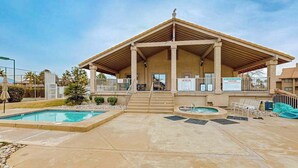 Um edifício com um espaço de estar coberto, duas piscinas e uma banheira de hidromassagem.