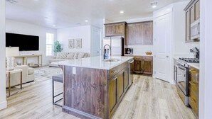A modern kitchen with a central island, wooden cabinets, and stainless steel appliances. - 5BR townhouse with lazy river pool (Washington)