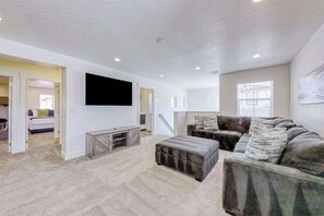 A modern living room with a flat-screen TV, a sectional sofa, and a small entertainment unit. - 5BR townhouse with lazy river pool (Washington)