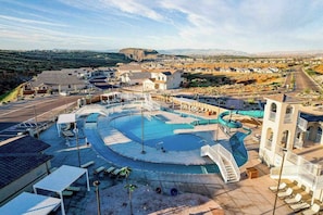 Um resort com uma piscina grande, áreas de descanso e vista para a paisagem ao redor.