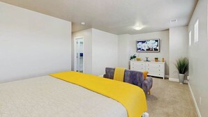 Ein Schlafzimmer mit einem großen Bett, einem Schminktisch, einem Fernseher und einer Zimmerpflanze.