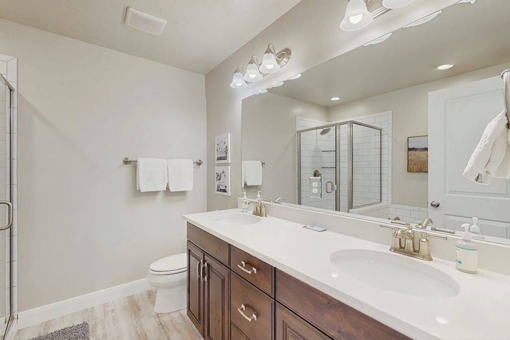 Un bagno moderno con un grande specchio, due lavabi e una zona doccia.