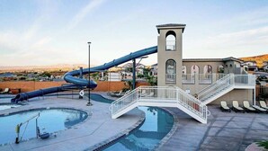 Ein Wasserpark mit einer großen Rutsche, einem Schwimmbecken und einem Gebäude mit einem Turm.