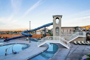 Ein Wasserpark mit einer großen Rutsche, einem Schwimmbecken und einem Gebäude mit einem Turm.
