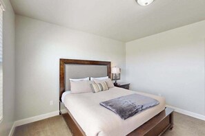 A bedroom with a large bed, a nightstand, and a wall-mounted lamp. - 3BR townhouse with hot tub and heated pool (Washington)