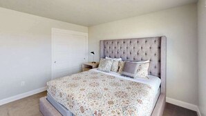 A bedroom with a tufted headboard, a patterned bedspread, and a bedside lamp. - 3BR townhouse with hot tub and heated pool (Washington)