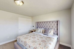 A bedroom with a tufted headboard, a patterned bedspread, and a bedside lamp. - 3BR townhouse with hot tub and heated pool (Washington)