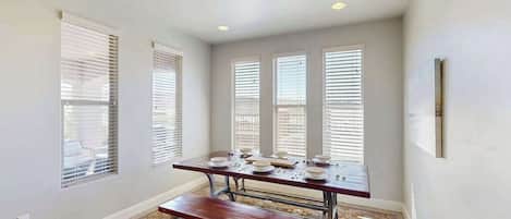 A dining area with a table set for four, a bench, and a patterned rug.