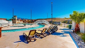 Zona de piscina con sillones de descanso, un puente y montañas al fondo.