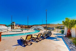 Ein Poolbereich mit Liegestühlen, einer Brücke und einem Bergpanorama.