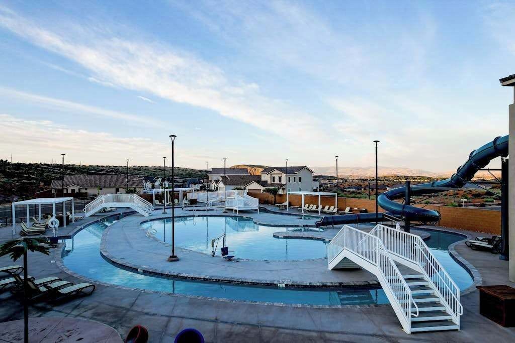 A swimming pool with a water slide and a white staircase.