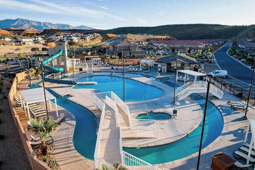 Un complex turístic amb una gran piscina, tobogan aquàtic i vistes a una zona residencial.