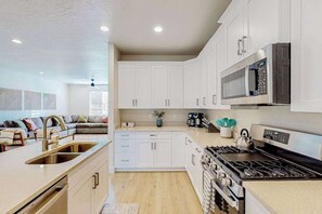 A modern kitchen with white cabinetry, a stainless steel stove, and a microwave. - Zion Retreat - Townhouse in Washington (Washington)
