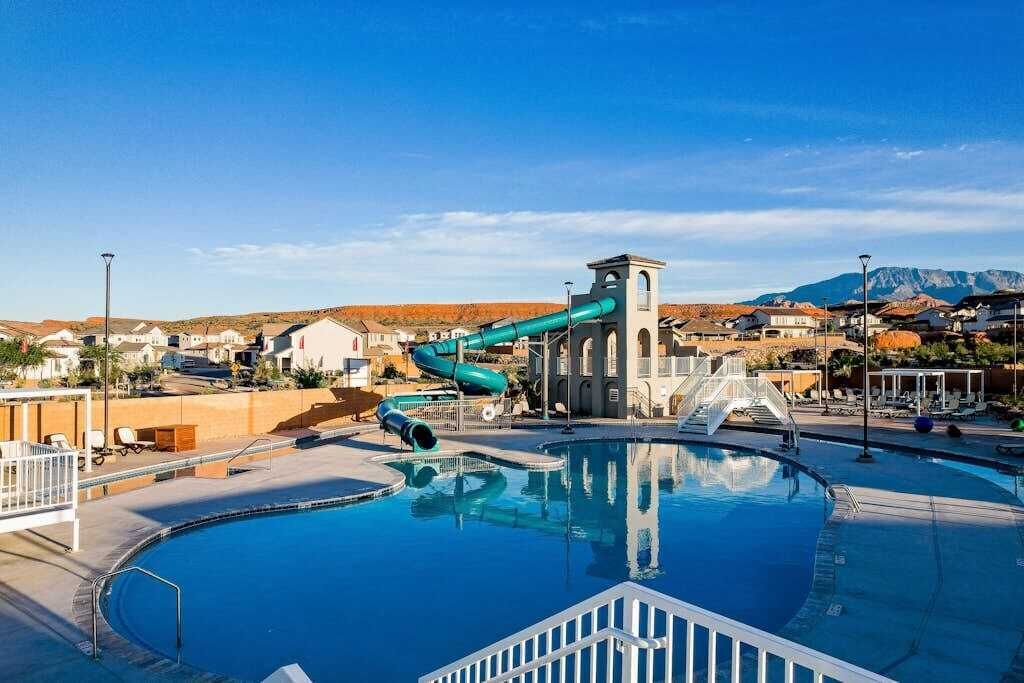 Piscina com escorrega e vista para uma área residencial ao fundo.