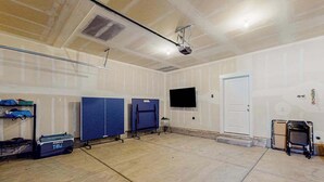 Amplio espacio interior con techo plano, un proyector montado y un televisor en la pared.