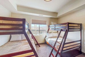 A room with three bunk beds, a window with blinds, and a ceiling light. - 3BR condo with pool, hot tub & pickleball court (St. George)