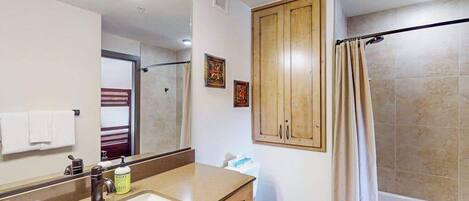 Un baño con lavamanos, espejo, armario, inodoro y cortina de ducha.